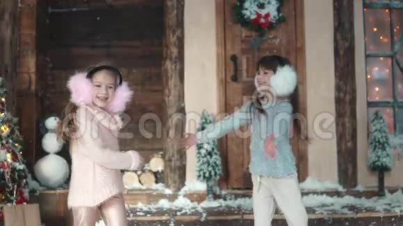 圣诞节或新年穿着轻便冬装的幼儿互相拥抱房子门廊上的两个小女孩视频的预览图
