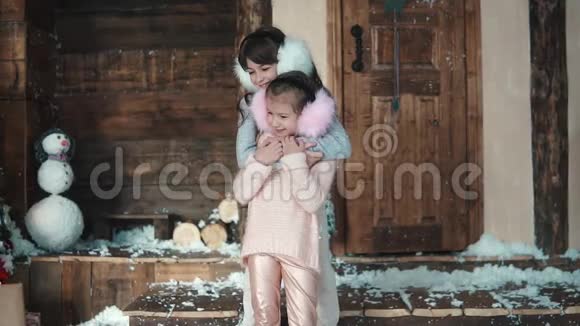 圣诞节或新年穿着轻便冬装的幼儿互相拥抱房子门廊上的两个小女孩视频的预览图
