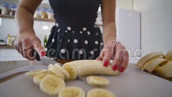 女人在家庭厨房的木制厨房板上切香蕉在家做饭厨房里的家庭气氛视频的预览图
