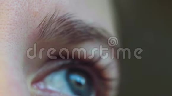 一个美丽的年轻女人的蓝眼睛看着窗户视频的预览图