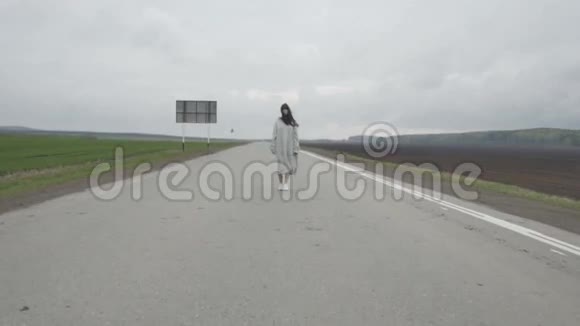 女人走在空荡荡的乡村道路上视频的预览图