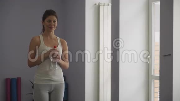 女孩在健身房里喝瓶子里的水视频的预览图