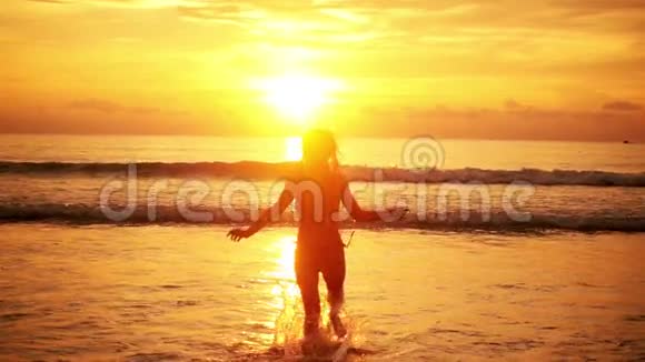 美丽快乐的女人在夕阳下的海面上奔跑视频的预览图