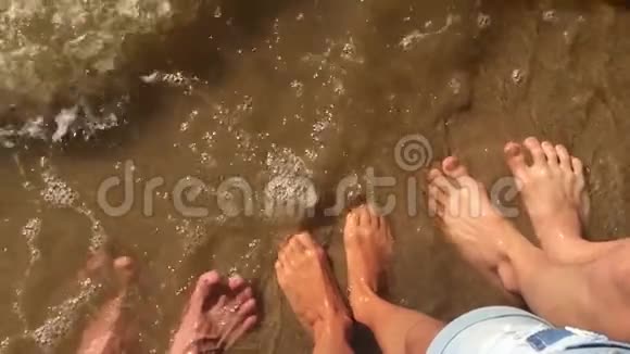 男孩女孩和男人的家庭腿在海洋水中慢动作视频强浪沙海休息家庭视频的预览图
