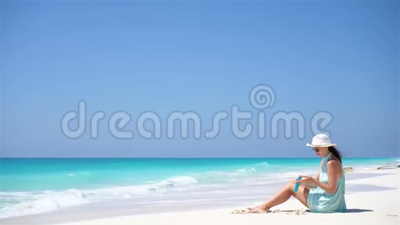 一位美丽的年轻女子手里拿着一束阳光躺在热带海滩上视频的预览图