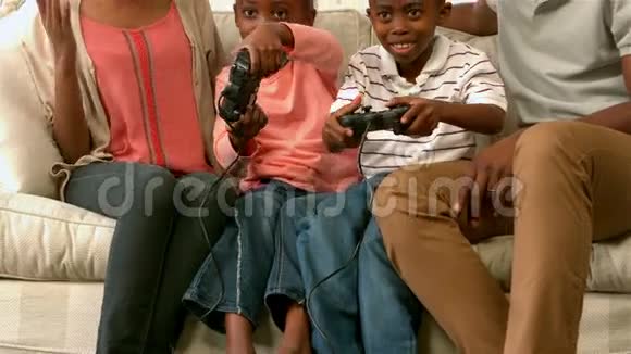 一家人在沙发上笑孩子们在玩电子游戏视频的预览图