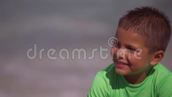 小孩在沙滩上玩沙子时对着妈妈笑视频的预览图