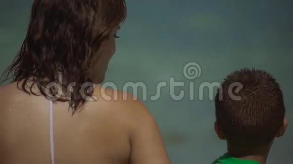 母亲和孩子在海边的海滩上交谈视频的预览图