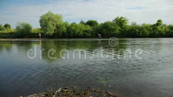 钓鱼两个人在河上钓鱼站在水里一股小小的水流视频的预览图