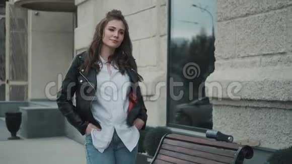 街上一个穿皮夹克的年轻女人的肖像时髦女孩在城里散步视频的预览图