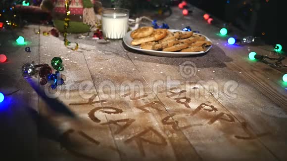 木制棕色桌子上面装饰着圣诞用品和花环圣诞节时一杯牛奶和一盘饼干视频的预览图