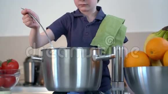 小男孩笑着在厨房里煮汤视频的预览图