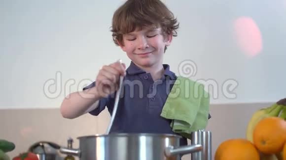 小男孩笑着在厨房里煮汤视频的预览图