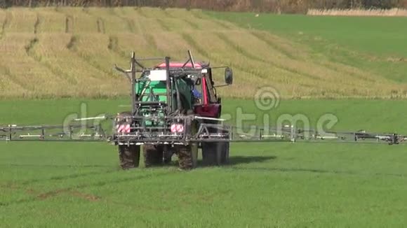 拖拉机喷洒秋季绿色麦田视频的预览图