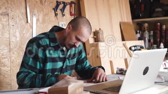 手工匠用笔记本电脑在他的木车间里画画视频的预览图