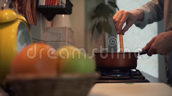 男人在厨房的炉子上用平底锅做饭用木勺搅拌视频的预览图