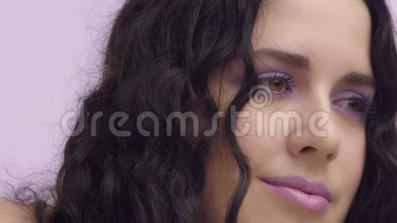 黑卷发加大小型棕色眼睛淡紫色背景淡紫色化妆视频的预览图