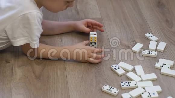 一个小男孩在房子的地板上玩多米诺骨牌的特写镜头视频的预览图