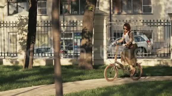 晴天在城市公园骑自行车的红发女子视频的预览图