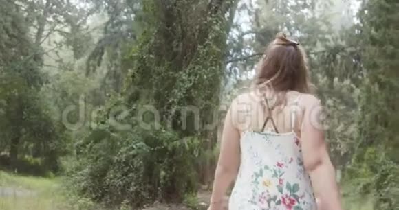 穿着白色裙子走在绿色森林里的年轻美女视频的预览图
