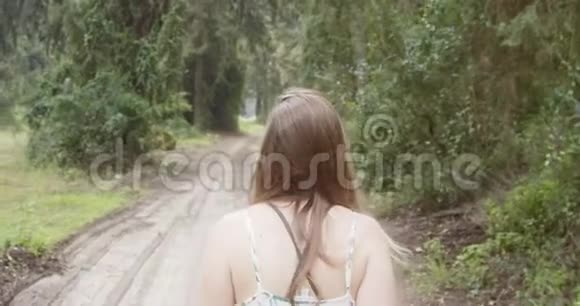 穿着白色裙子走在绿色森林里的年轻美女视频的预览图