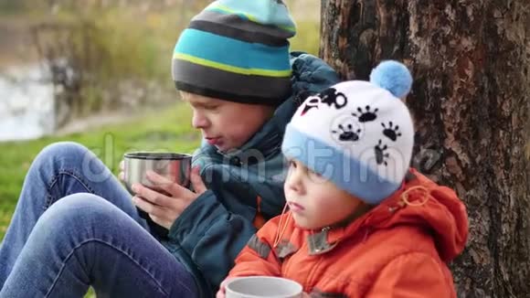 在秋天的公园里孩子们坐在草坪上喝热茶在新鲜的空气中散步视频的预览图