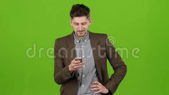 家伙看着照片里的手机玩得很开心绿色屏幕视频的预览图