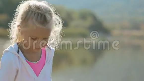一个金发女孩把石头扔进水里视频的预览图