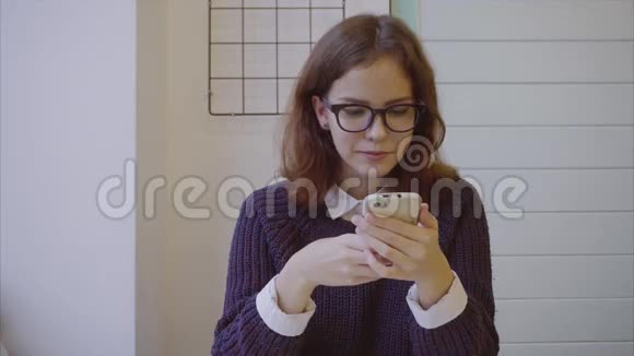 年轻漂亮的女学生在咖啡馆里用她的智能手机发短信视频的预览图