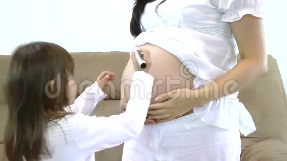 小女孩在孕妇肚子上画着快乐的笑脸视频的预览图