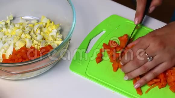 带有蔬菜和蛋黄酱的俄罗斯肉沙拉一个女人在切割板上切一个煮熟的胡萝卜视频的预览图