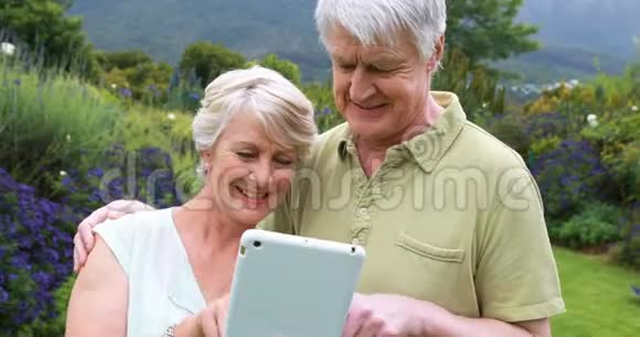 在花园里使用数码平板电脑的老夫妇视频的预览图