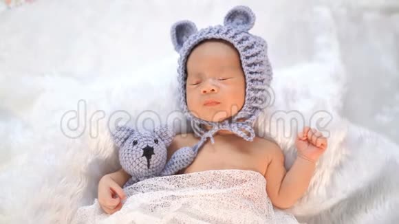 头戴熊帽子的新生婴儿睡在毛皮床上视频的预览图