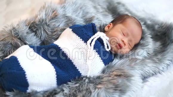 一个刚出生的小男孩睡在床上用编织的包裹裹着襁褓视频的预览图