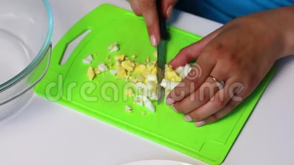 带有蔬菜和蛋黄酱的俄罗斯肉沙拉一个女人在切割板上切一个煮鸡蛋视频的预览图