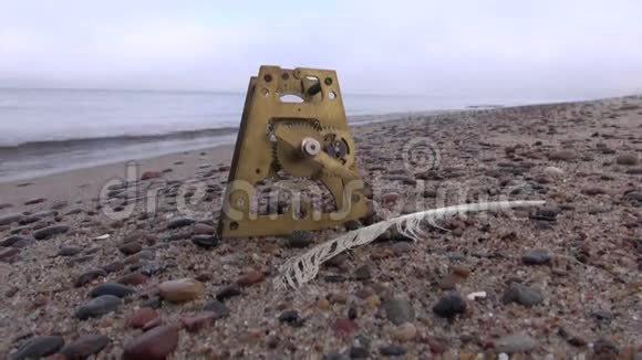 海滩沙滩上的古时钟铜器和海鸥羽毛视频的预览图