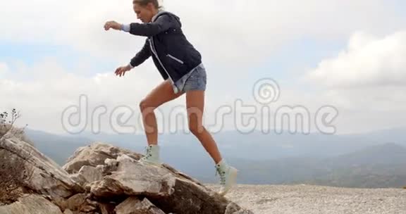 站在岩石顶部的运动女子视频的预览图
