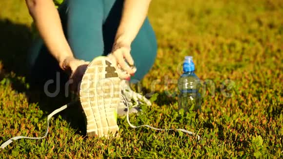 女孩停止跑步把鞋带系在跑鞋上健身女孩在户外训练4K视频的预览图