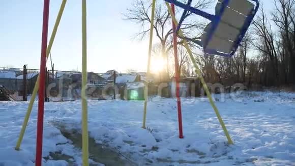 为孩子们荡秋千在操场上荡秋千雪的阳光照耀着冬天视频的预览图