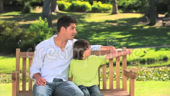 父亲和儿子坐在公园长椅上视频的预览图