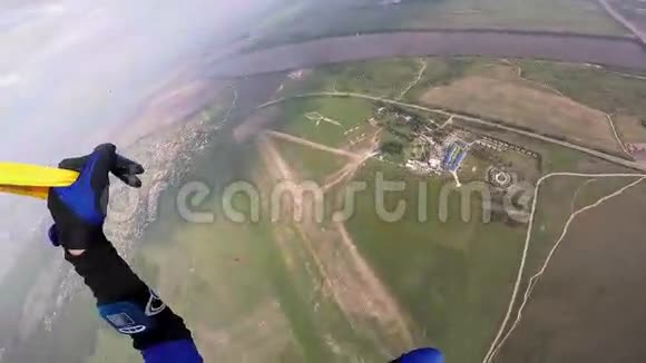 专业的跳伞运动员在绿色的田野河流上空飞翔晴天景观视频的预览图