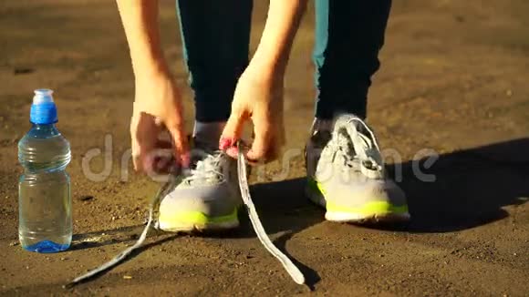 女孩停止跑步把鞋带系在跑鞋上健身女孩在户外训练4K视频的预览图