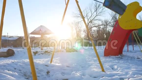 为孩子们荡秋千在操场上荡秋千阳光灿烂白雪皑皑冬天视频的预览图