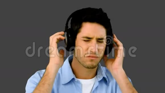 戴着耳机在灰色背景下听音乐的人视频的预览图