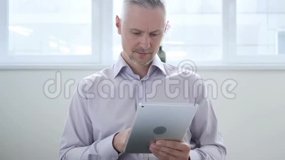 中年男子在办公室的平板电脑上浏览互联网视频的预览图