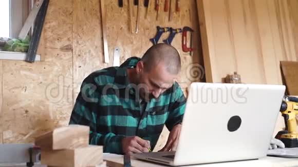 手工匠用笔记本电脑在他的木车间里画画视频的预览图