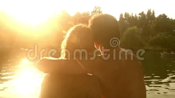 一对相爱的情侣在日落时分坐在河边自拍接吻视频的预览图