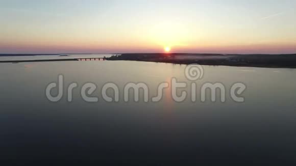 4K早春日落时乘桥飞越大型冰冻湖泊空中飞行视频的预览图