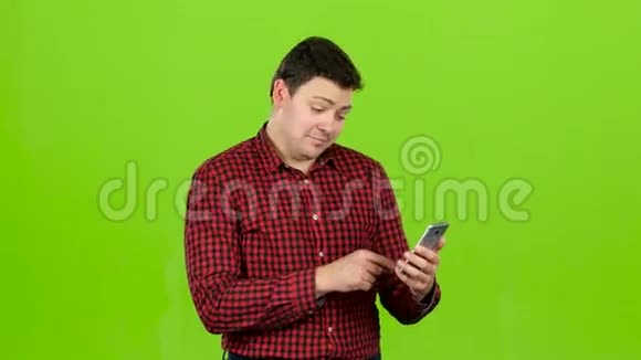 家伙看着照片里的手机玩得很开心绿色屏幕视频的预览图