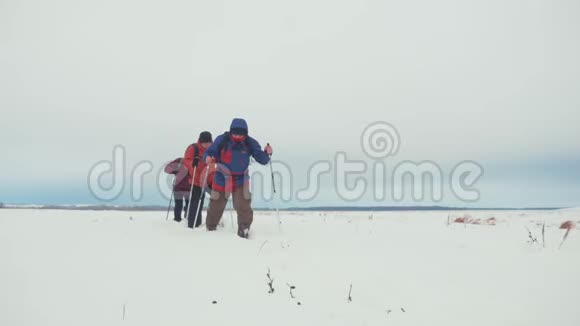 三个徒步旅行者带着徒步旅行杆一个背包和雪鞋徒步旅行者小组冬季旅行愉快视频的预览图